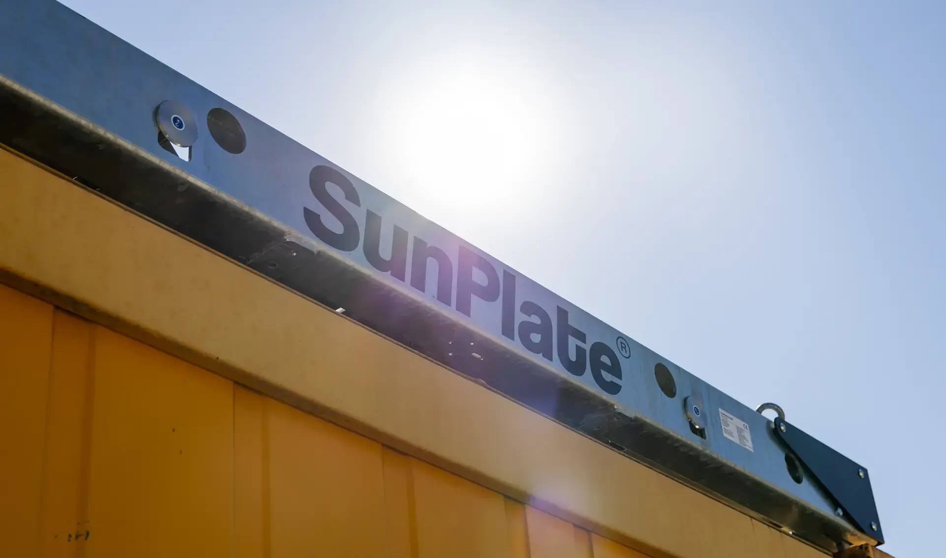 SunPlate auf gelben Container mit blauem Himmel Sonne im Hintergrund